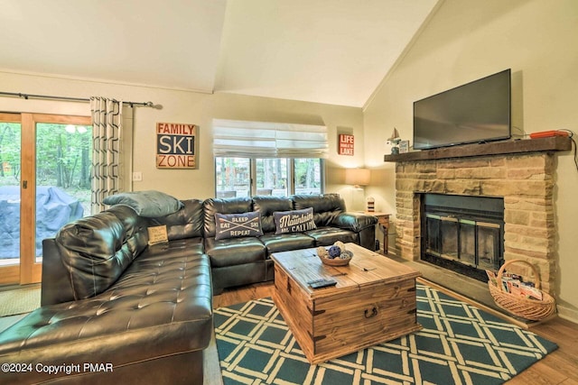 living area with a stone fireplace, wood finished floors, and high vaulted ceiling