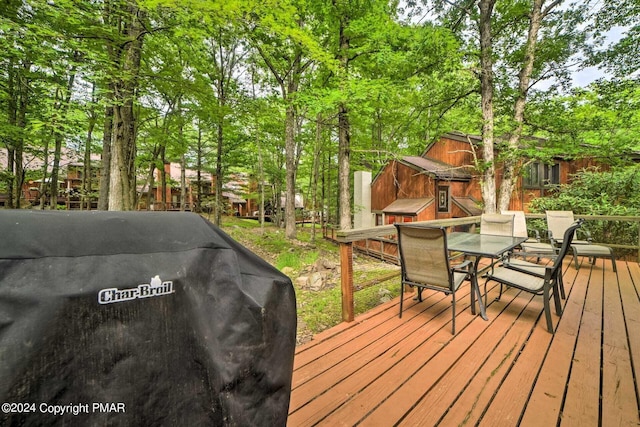 wooden deck featuring outdoor dining space and a grill