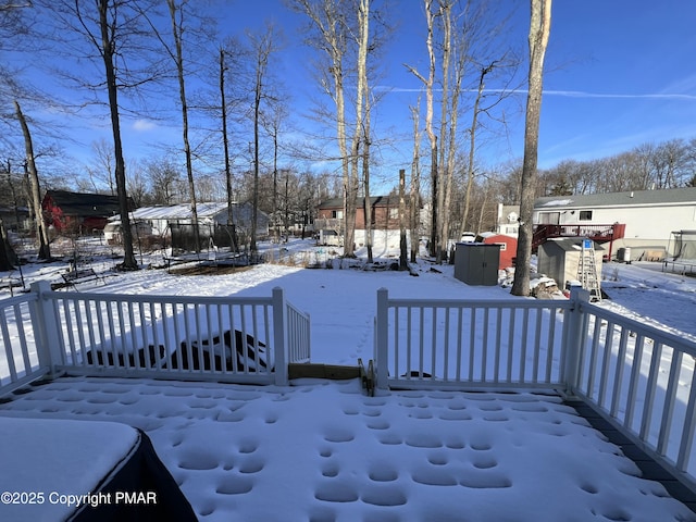 yard layered in snow with a trampoline