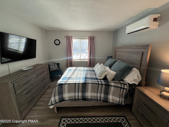 bedroom featuring an AC wall unit, dark wood finished floors, and a textured ceiling