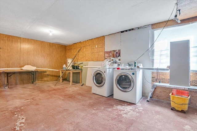washroom featuring laundry area, wood walls, and washer and clothes dryer