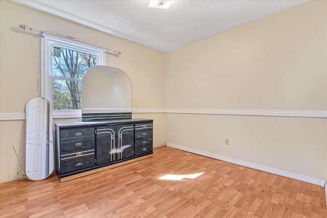 interior space featuring light wood-style floors, a textured ceiling, and baseboards