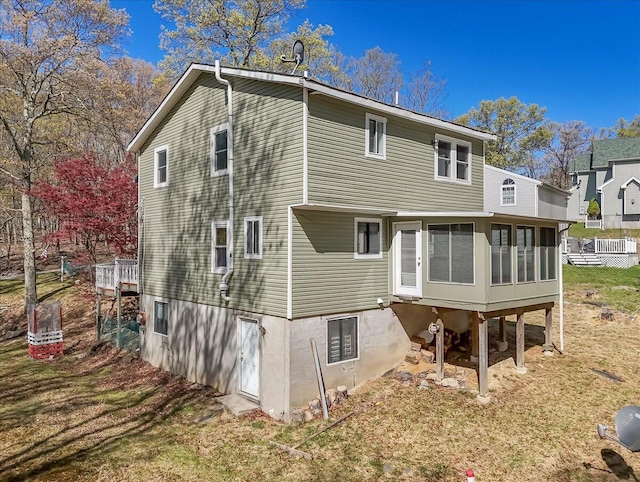 rear view of property featuring a yard and a sunroom