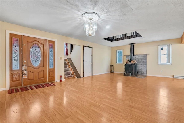 entrance foyer featuring a wood stove, baseboards, wood finished floors, and stairway