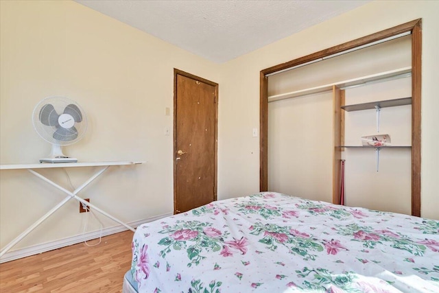 bedroom featuring baseboards, wood finished floors, and a closet