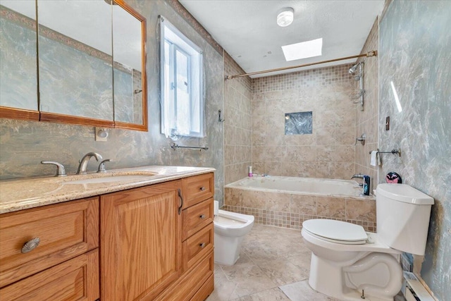 full bathroom featuring vanity, toilet, tiled shower / bath, baseboard heating, and a skylight