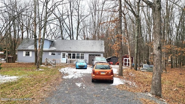 view of front of property featuring aphalt driveway, an outbuilding, and a storage unit