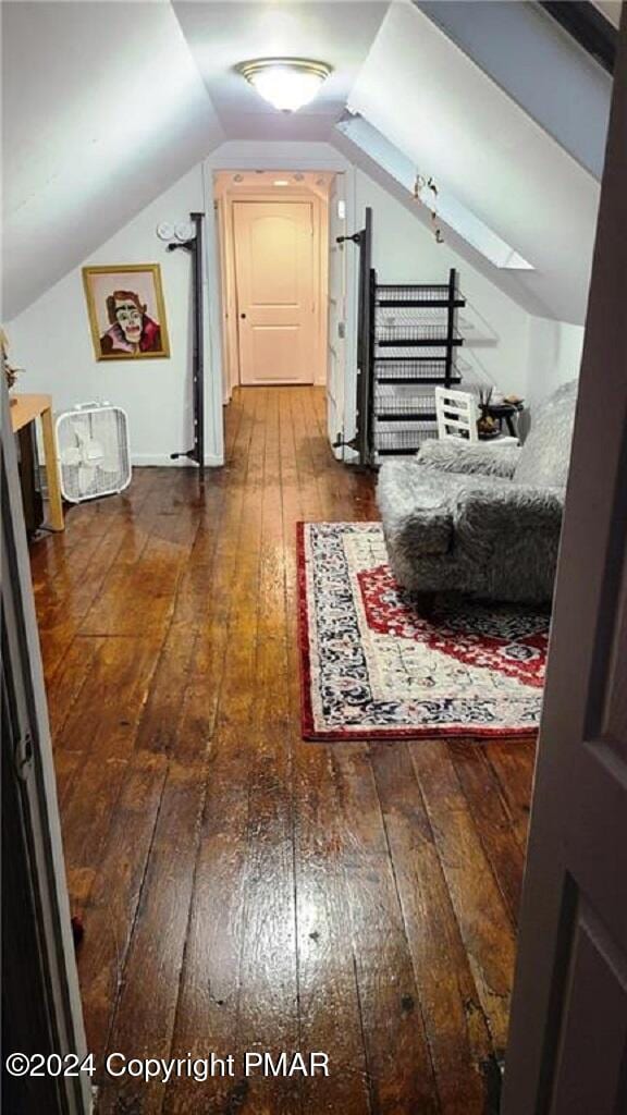 hallway with lofted ceiling and hardwood / wood-style flooring