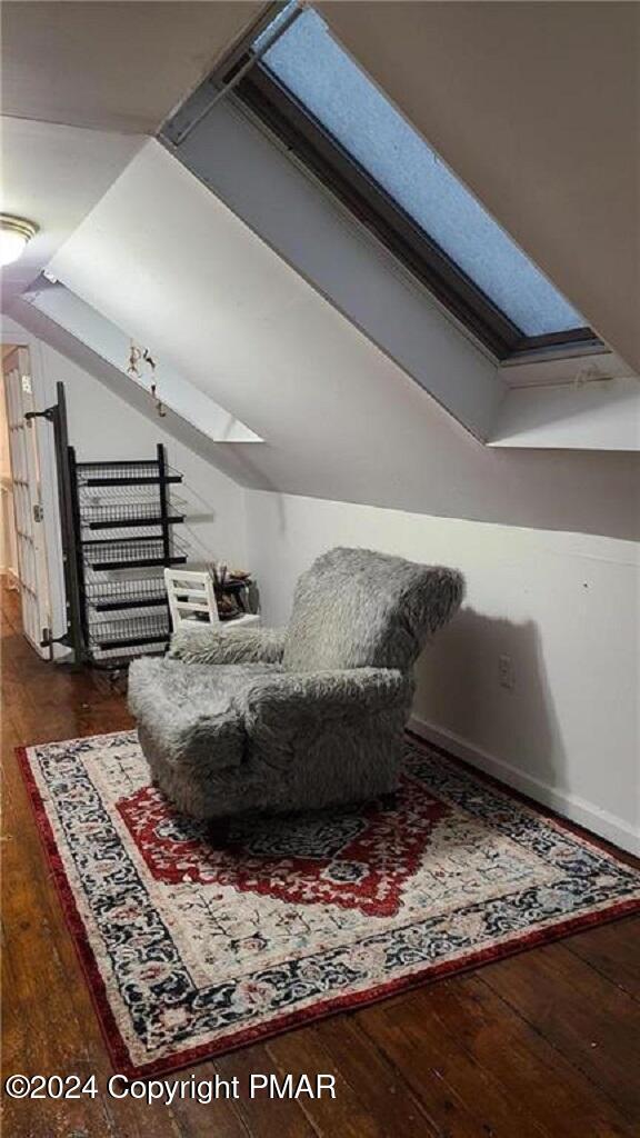 sitting room with vaulted ceiling with skylight and hardwood / wood-style floors