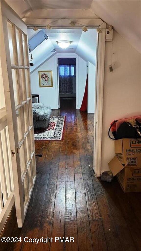 corridor featuring vaulted ceiling and dark wood-type flooring