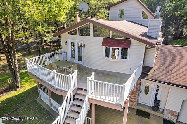 rear view of property with stone siding, stairway, a shingled roof, a wooden deck, and a chimney