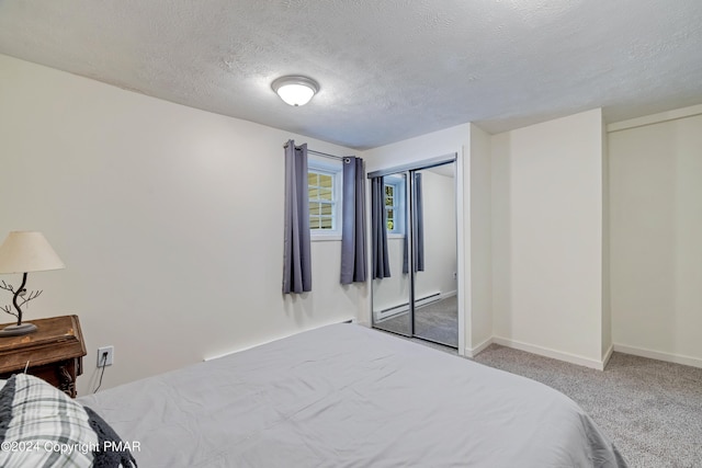 bedroom featuring a baseboard heating unit, carpet floors, a textured ceiling, and baseboards