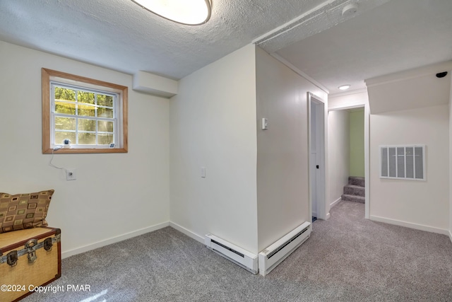 below grade area with visible vents, a baseboard heating unit, baseboards, carpet, and a textured ceiling