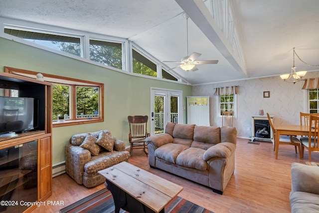 living room featuring a wealth of natural light, light wood-style floors, vaulted ceiling with beams, and ceiling fan with notable chandelier