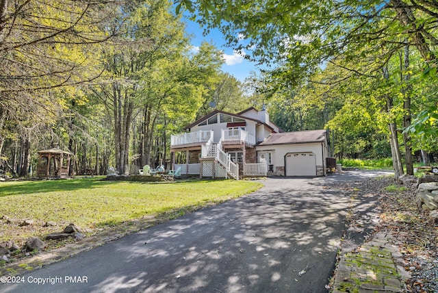 view of front facade with driveway, a front lawn, a gazebo, an attached garage, and stairs