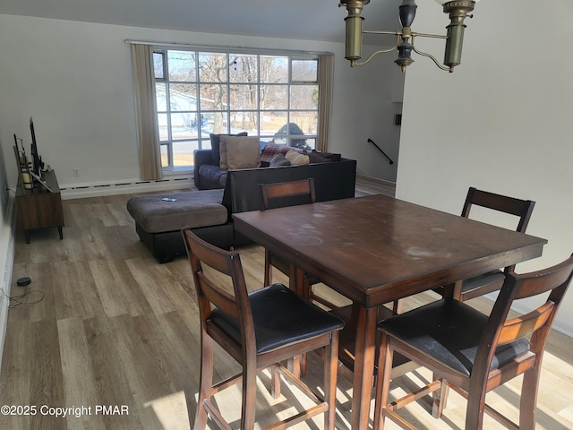 dining room featuring light wood finished floors, a baseboard radiator, and a notable chandelier