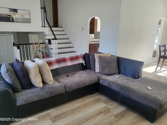 living room featuring arched walkways, wood finished floors, and stairs