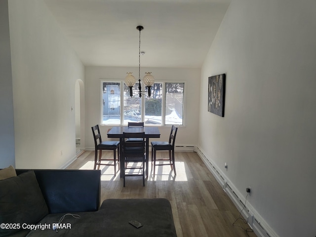 dining room featuring arched walkways, a notable chandelier, lofted ceiling, a baseboard heating unit, and wood finished floors