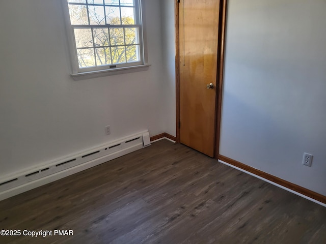 empty room featuring a baseboard radiator, baseboards, and dark wood-type flooring