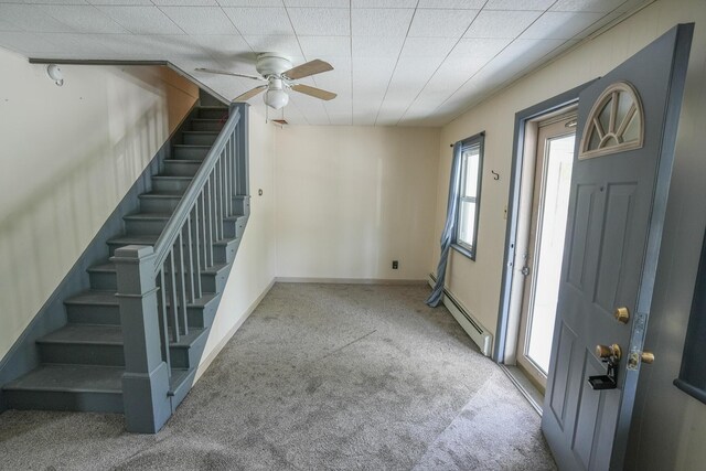 entrance foyer with carpet floors, a ceiling fan, stairs, and a baseboard heating unit