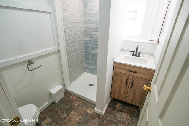 bathroom featuring vanity, toilet, and tiled shower