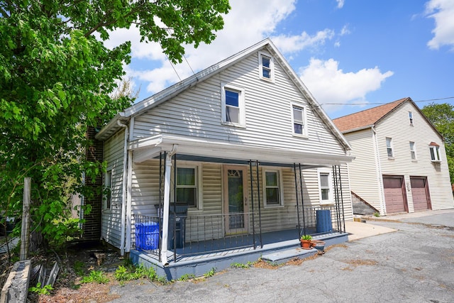 view of front of house with a porch, aphalt driveway, an attached garage, and a chimney
