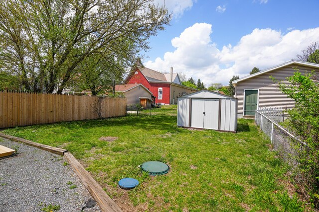 view of yard with an outdoor structure, a fenced backyard, and a shed