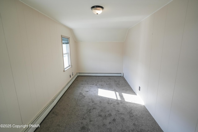 carpeted spare room with vaulted ceiling and a baseboard heating unit