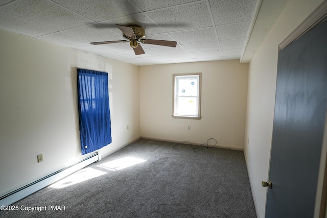 carpeted spare room featuring baseboard heating, ceiling fan, and a paneled ceiling