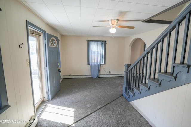 entryway featuring a baseboard heating unit, ceiling fan, a healthy amount of sunlight, and dark colored carpet