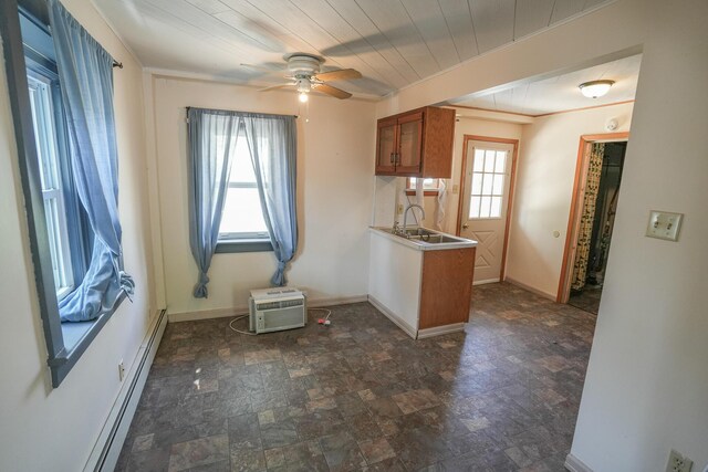 kitchen featuring ceiling fan, brown cabinetry, baseboards, stone finish flooring, and a baseboard heating unit