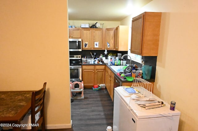 kitchen with dark wood-style floors, brown cabinets, stainless steel microwave, a sink, and range