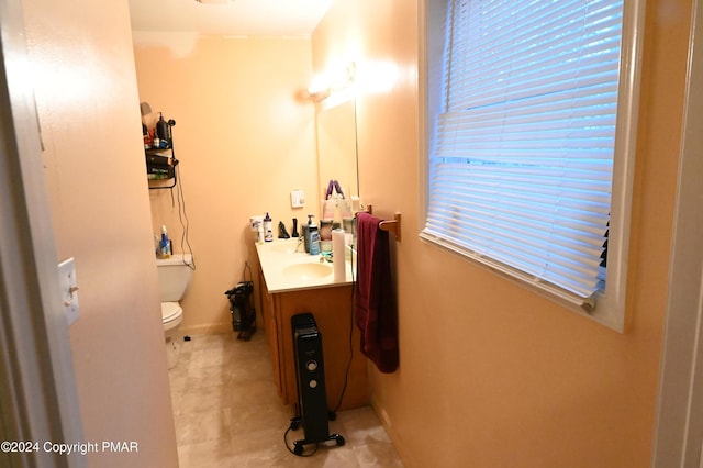 half bath featuring baseboards, vanity, and toilet