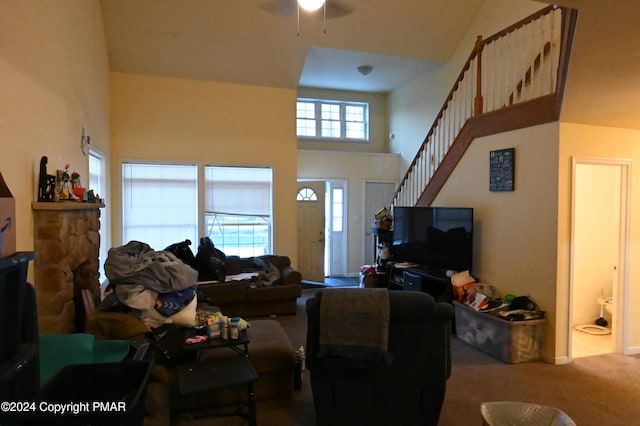 living area with carpet floors, stairway, and a towering ceiling