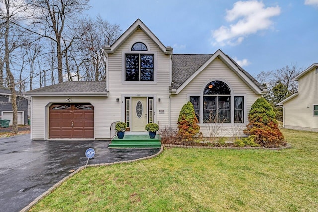 traditional home with a front lawn, a shingled roof, an attached garage, and aphalt driveway
