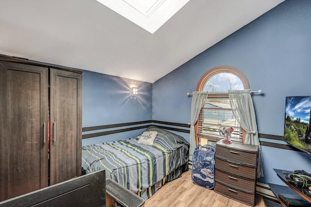 bedroom with lofted ceiling with skylight and wood finished floors