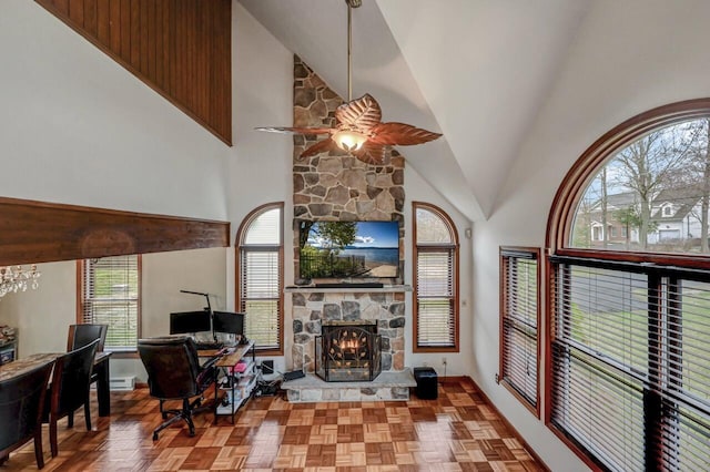 living area featuring a fireplace, a ceiling fan, high vaulted ceiling, and baseboards