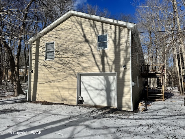 snow covered property with a garage and stairs