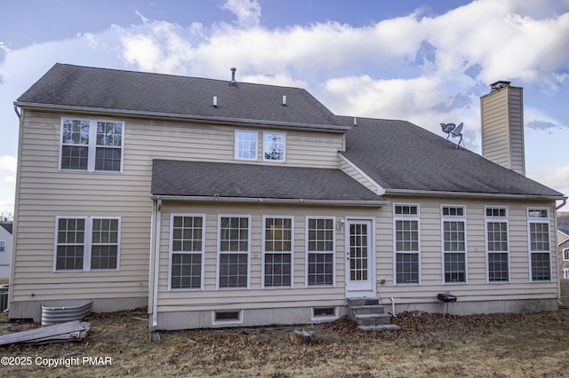 back of property with entry steps, roof with shingles, and a chimney