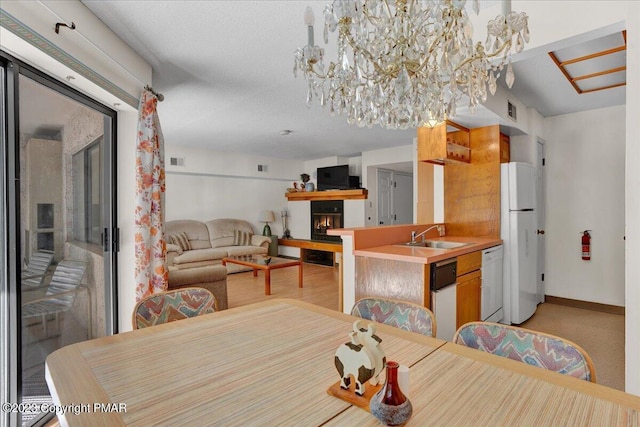 dining area featuring a chandelier, visible vents, a lit fireplace, and baseboards