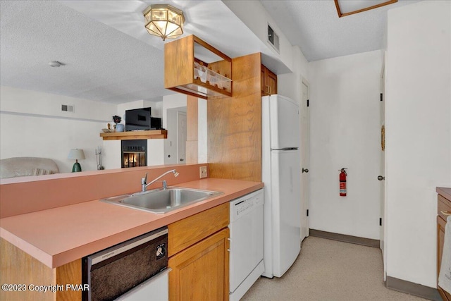 kitchen with a textured ceiling, white appliances, a sink, visible vents, and light countertops