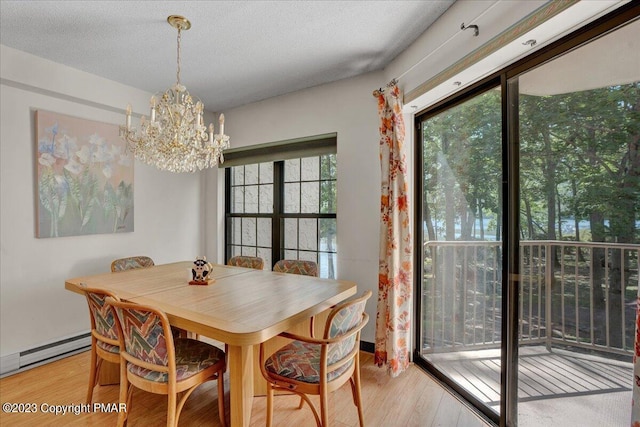 dining room with light wood finished floors, a chandelier, a textured ceiling, and a baseboard heating unit