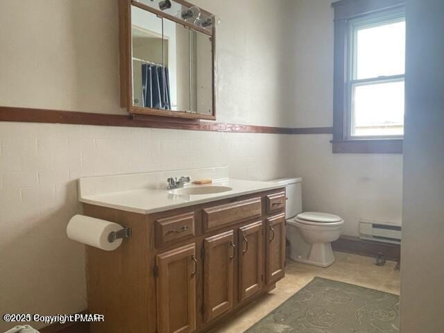 full bath with a baseboard radiator, toilet, a wainscoted wall, vanity, and tile walls