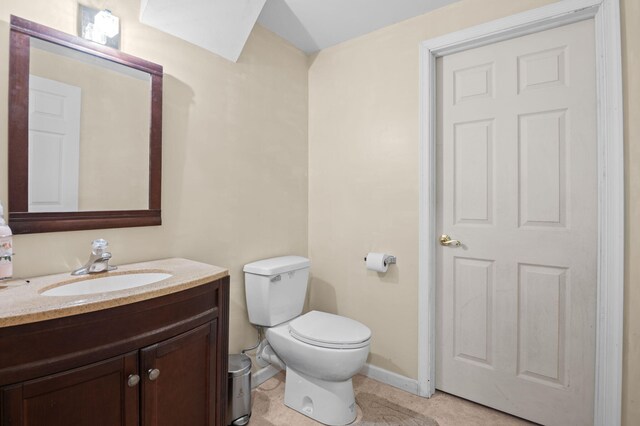 half bathroom featuring toilet, tile patterned flooring, vanity, and baseboards