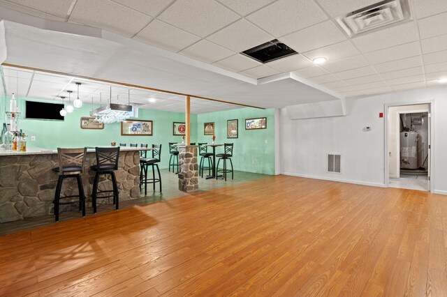 interior space with gas water heater, indoor wet bar, visible vents, and hardwood / wood-style floors