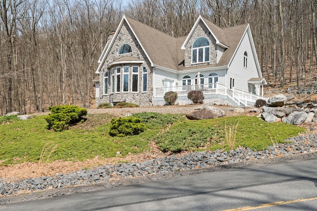 view of front of property featuring a porch, stone siding, and a shingled roof