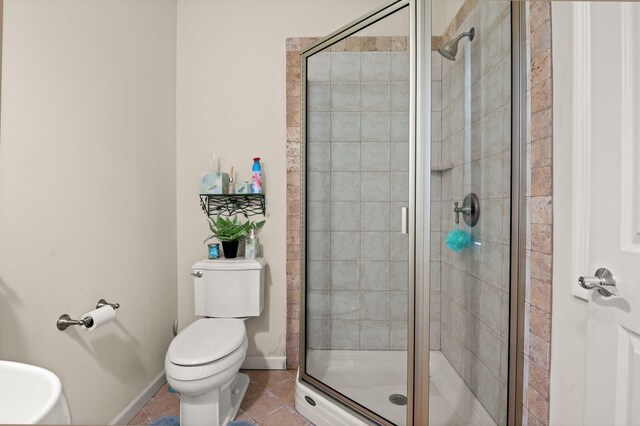 full bath featuring baseboards, a stall shower, tile patterned floors, and toilet