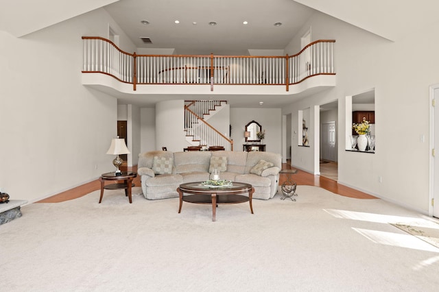carpeted living room with visible vents, baseboards, recessed lighting, a high ceiling, and stairway
