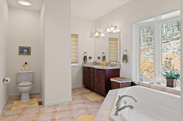 bathroom with stone tile floors, a sink, double vanity, baseboards, and a bath