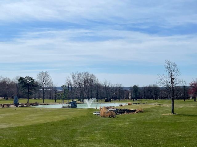 view of home's community with a water view, a yard, and golf course view